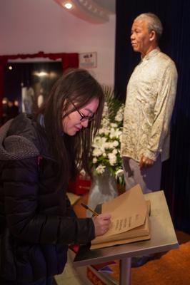 游客在上海杜莎夫人蠟像館曼德拉蠟像邊的吊唁本上寫下唁詞，寄托哀思